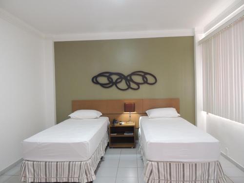 two beds in a room with two olympics on the wall at Star Hotel in Itaperuna