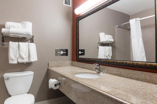 W łazience znajduje się umywalka, toaleta i lustro. w obiekcie LeBossier Hotel w mieście Bossier City