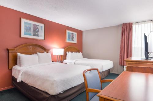 two beds in a hotel room with red walls at LeBossier Hotel in Bossier City