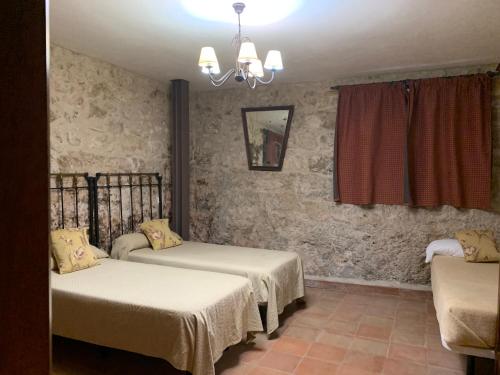 a room with two beds and a chandelier at Molino Grande del Duratón in San Miguel de Bernúy
