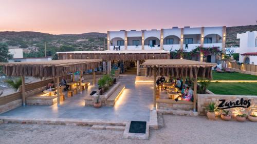 a resort with people sitting on benches and tables at Zanetos Prasonisi in Prasonisi