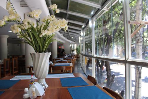 a dining room with a table with a vase of flowers at Realminas Hotel e Restaurante in Governador Valadares