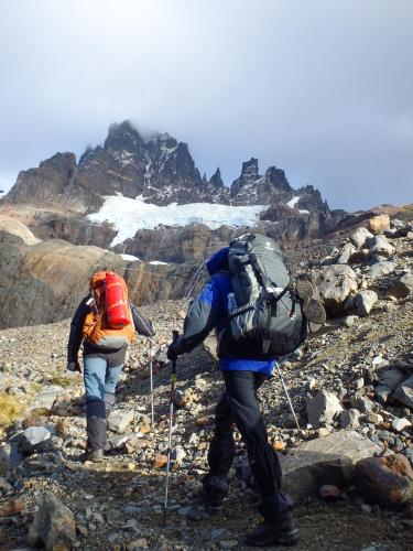 two people with backpacks walking on a rocky mountain at Casa Cerro Castillo in Villa Cerro Castillo