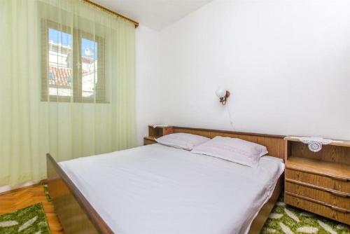 a bedroom with a bed with white sheets and a window at Apartments Jerkica - 50 m from sea in Sutivan