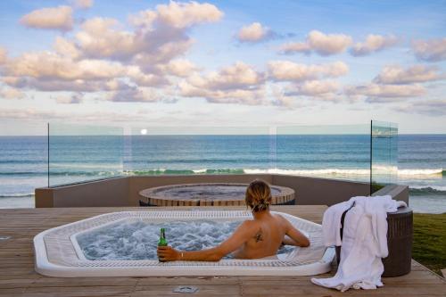 a man sitting in a hot tub looking at the ocean at Bay Lodge on the Beach in Mossel Bay