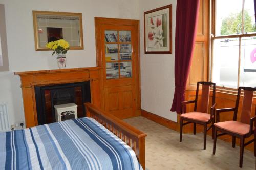 a bedroom with a bed and a fireplace at Carnegie Holiday Cottage in Dunfermline