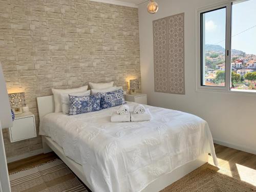 um quarto com uma cama branca com duas toalhas em Little Townhouse Funchal no Funchal