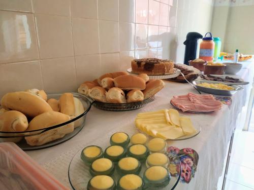 a table topped with different types of bread and pastries at Pousada NP in Conceição da Barra