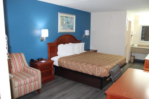 Habitación de hotel con cama y silla en Americas Best Value Inn Tuscaloosa en Tuscaloosa