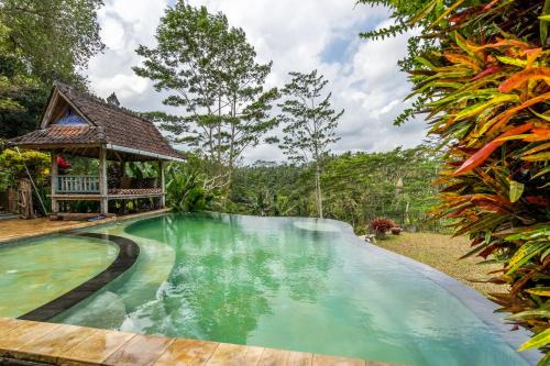 a swimming pool in front of a house with a gazebo at Tirta Asri Ubud Villa in Ubud