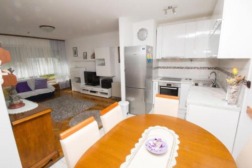 uma cozinha com uma mesa de madeira e uma cozinha com armários brancos em Apartment Jerko - 200 m from beach em Omiš
