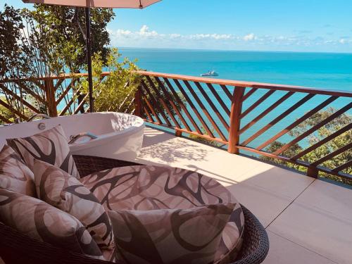 a chair on a balcony with a view of the ocean at Altavista residence in Morro de São Paulo