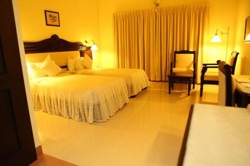 a hotel room with two beds and a chair at Hotel Airlink Castle in Nedumbassery