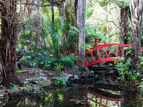 a red bridge over a pond in a garden at Waimoana Garden Accommodation in Whangarei