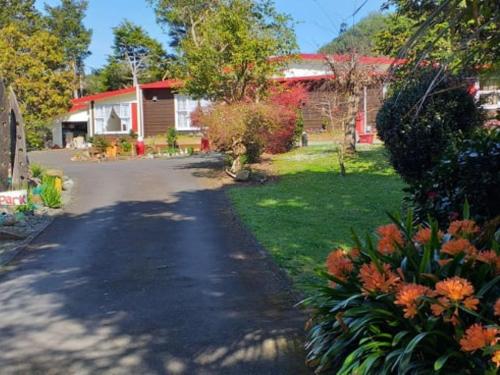 a driveway leading to a house with a red roof at Waimoana Garden Accommodation in Whangarei