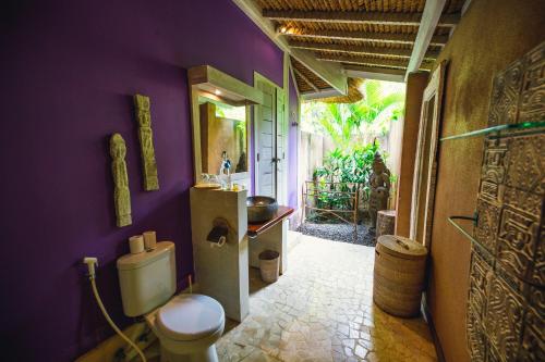 a bathroom with a toilet and a purple wall at Maylie Bali Villa & Bungalows in Canggu