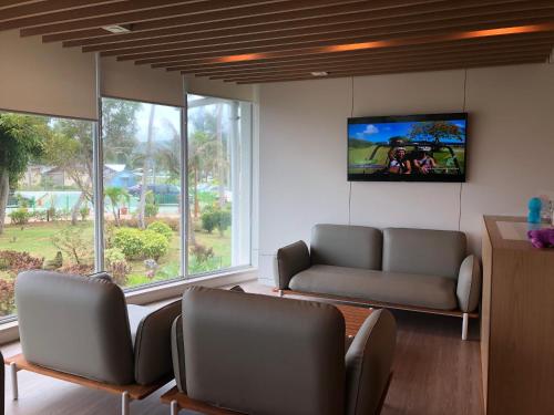 a living room with two couches and a flat screen tv at Saipan World Resort in Susupe