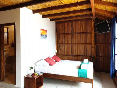 a bedroom with a bed with a wooden wall at Cocoa Inn Hostal in Canoa