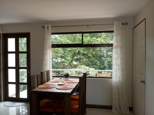 comedor con mesa y ventana grande en CASA GERANIOS # 2, en Monteverde