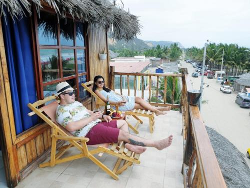 two people sitting in chairs on a balcony at Cocoa Inn Hostal in Canoa