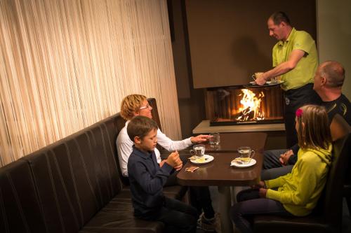 un grupo de personas sentadas alrededor de una mesa en un restaurante en Hotel Center Pokljuka en Goreljek