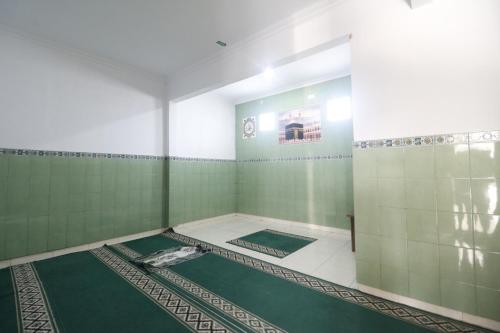 y baño con paredes de azulejos verdes y blancos. en RedDoorz Plus @ Jalan Parangtritis 2, en Yogyakarta