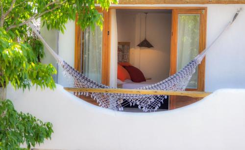 a hammock hanging from a window in a house at Pousada Chez Toi in Jericoacoara