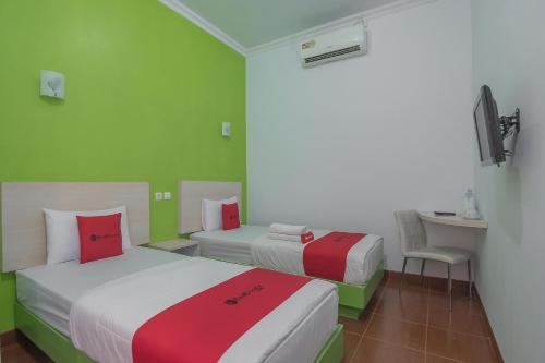 two beds in a room with green and red at RedDoorz Plus near Alun Alun Kuningan in Kuningan