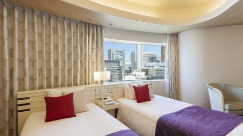 2 bedden in een hotelkamer met een raam bij Hotel Elsereine Osaka in Osaka