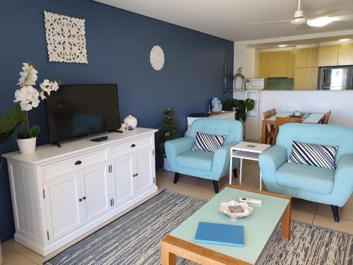 a living room with a tv and two blue chairs at Azure Sea Whitsunday Resort in Airlie Beach