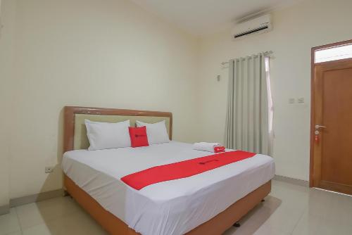 a bedroom with a bed with a red blanket on it at RedDoorz near IPDN 2 in Sumedang