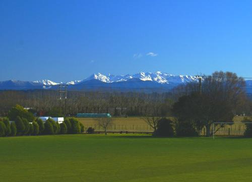 a green field with snow capped mountains in the background at Parkside Motel in Richmond