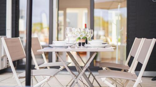 een witte tafel met stoelen en wijnglazen bij Luxury Apart' MONS City Center with Terrace in Bergen