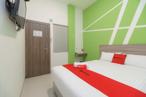 - une chambre avec un grand lit et une couverture rouge dans l'établissement RedDoorz Plus at Grand Tara Homestay Palembang, à Palembang
