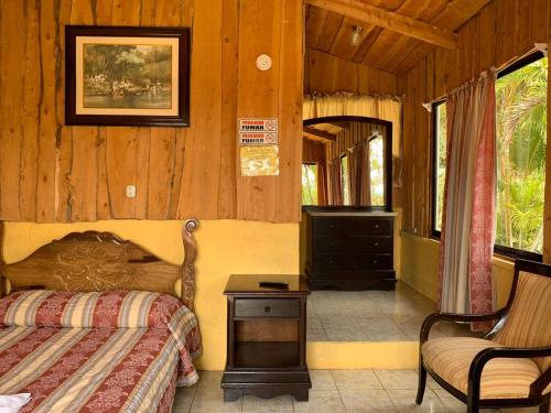 1 dormitorio con 1 cama, vestidor y silla en Hotel Palenque Tarrazu en San Marcos
