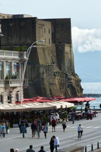 a group of people walking on a street near a castle at Partenope Relais in Naples