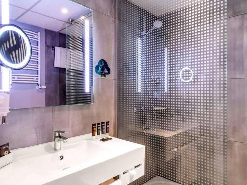 a bathroom with a sink and a shower with a mirror at Novotel Warszawa Airport in Warsaw