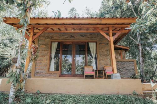 a house with a wooden pergola and two chairs at Saridevi Ecolodge in Jatiluwih