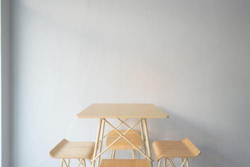a table and two stools in front of a white wall at RedDoorz Plus Syariah @ Raya Nginden 2 in Surabaya