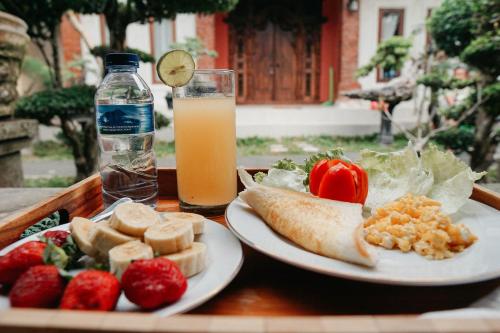 une table avec deux assiettes de nourriture et un verre de jus d'orange dans l'établissement HOKYY Accommodation, à Ubud