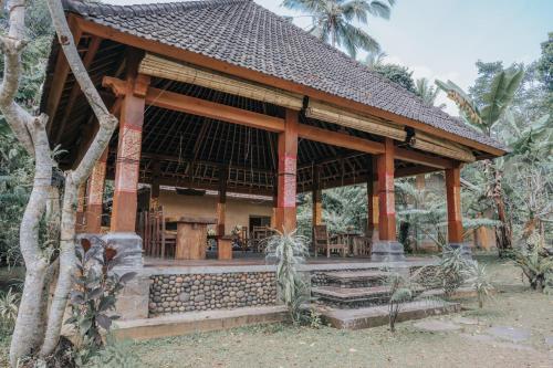 a wooden pavilion with stairs in a forest at Saridevi Ecolodge in Jatiluwih
