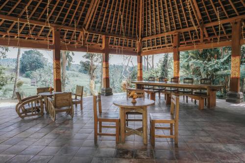 a dining room with tables and chairs in a building at Saridevi Ecolodge in Jatiluwih