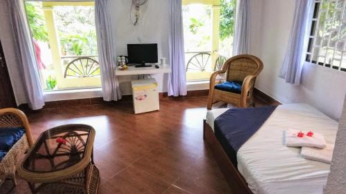 a bedroom with a bed and chairs and windows at Q Bungalows in Kep