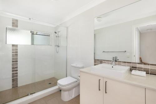een witte badkamer met een toilet en een wastafel bij Coral Beach Noosa Resort in Noosaville