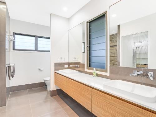 a bathroom with two sinks and a large mirror at WATERFRONT HOME BORDERING MOOLOOLABA in Buddina