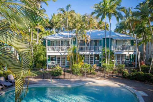 an exterior view of a house with palm trees and a swimming pool at Coral Beach Noosa Resort in Noosaville