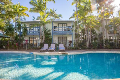 a swimming pool with two chairs and a building at Coral Beach Noosa Resort in Noosaville