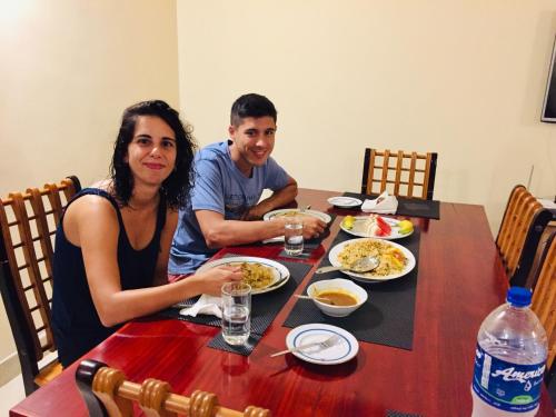 a man and a woman sitting at a table with food at Sweet Home Tourist Rest, Cooking Classes & Tours in Anuradhapura