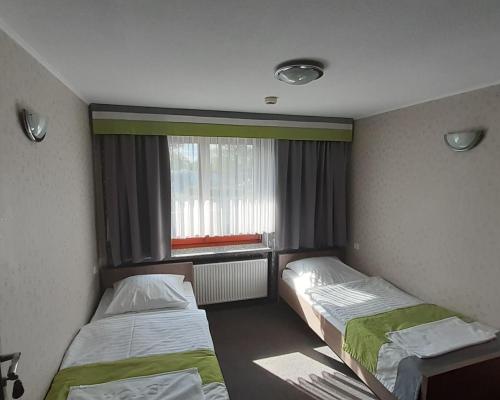 two beds in a small room with a window at Restauracja i hotel Pod Kasztanami in Opole