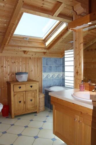 La salle de bains est pourvue d'un lavabo, d'une baignoire et d'une lucarne. dans l'établissement Chalet traditionnel Alpes, à Bernex